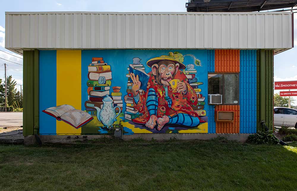 Close up of Jiffy lube Mural featuring colorful books and a chimpanzee drinking tea and reading