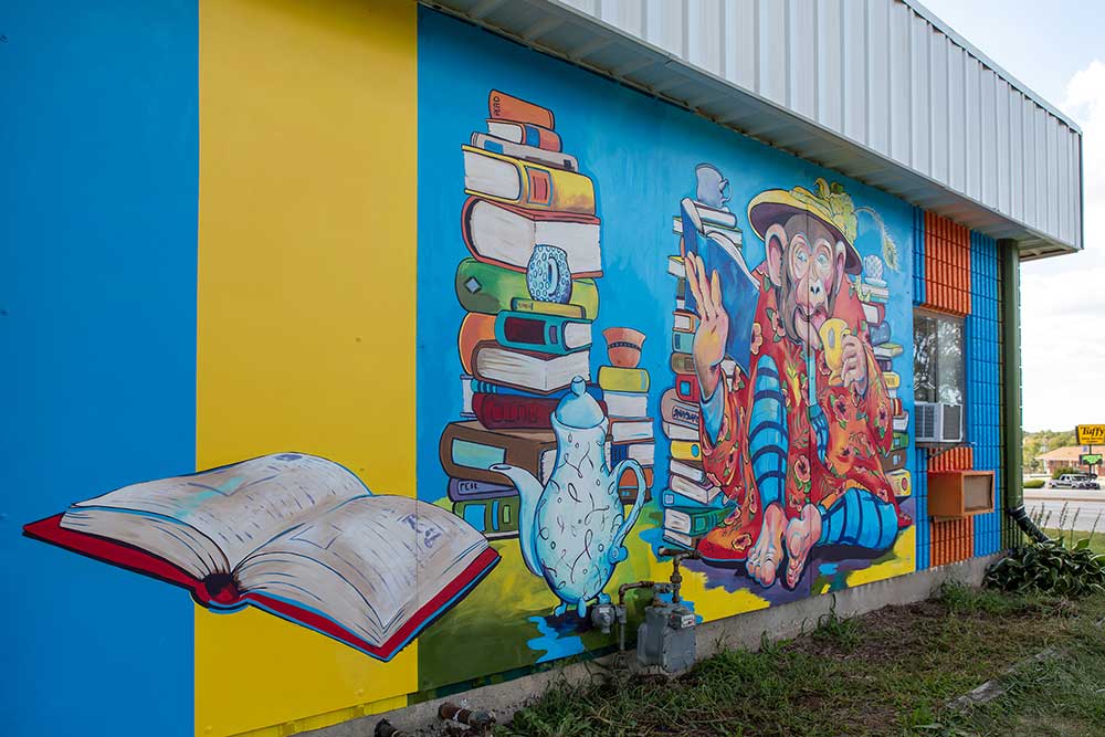 Close up of colorful mural of Chimpanzee drinking tea surrounded by books