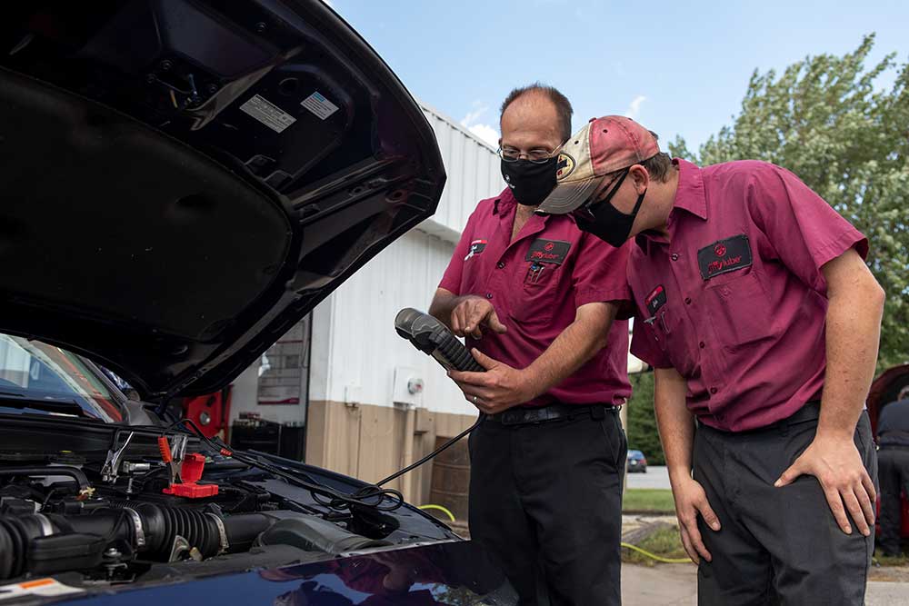 two jiffy lube employees checking battery in vehicle